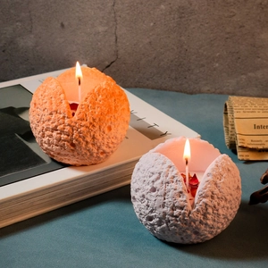 Dettaglio di candele sferiche a cratere lunare con petali e stoppino acceso caldo