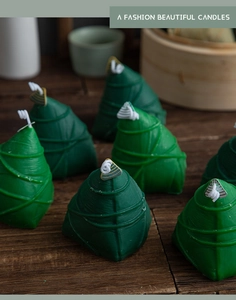 Close-up of green bamboo zongzi shaped scented candles on a dark wooden table decor