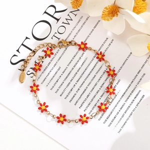 Detail view of gold stainless steel chain bracelet with red enamel daisy flower charms