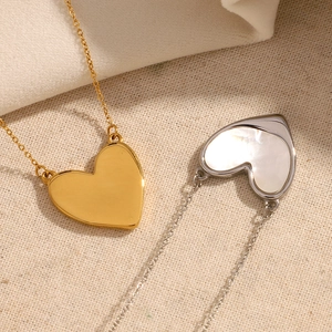 Close-up of gold shell heart necklace and silver pendant on beige linen fabric