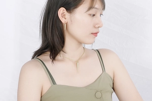 Close-up of a model wearing a golden conical pendant necklace and matching earrings