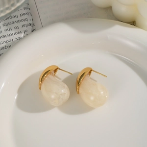 Elegant gold metal and marble beige resin teardrop earrings in a white ceramic dish
