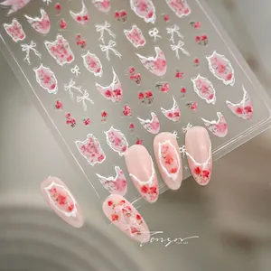 Macro shot of 3D embossed floral nail stickers with lace bows and French tips
