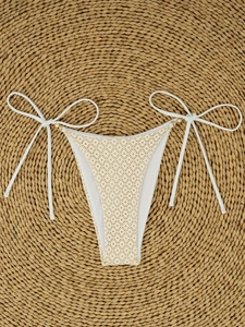 Detailed flat lay of crochet bikini bottom with side ties and pearl bead accents