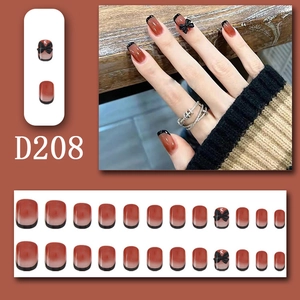 Macro detail of red gradient press-on nails with 3D black bows and French tip style