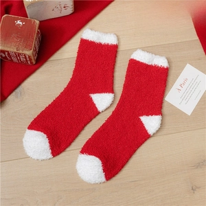 Flat lay of soft red and white fuzzy Christmas socks on a warm wooden background