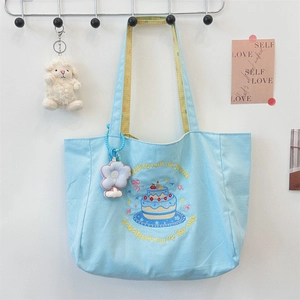 Detail of blue canvas tote bag with cake embroidery and yellow checkered fabric lining
