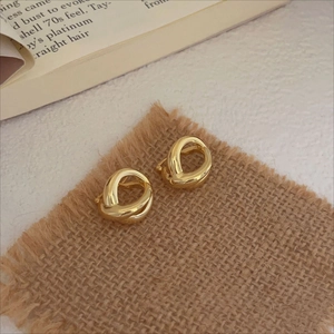 Detail of gold twisted rope hoop earrings resting on rustic brown linen fabric