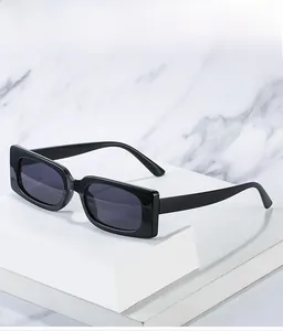 Detail view of rectangular black sunglasses on a marble texture and geometric stand