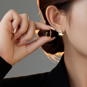 Detailed view of gold irregular geometric textured earrings on a model's ear lobe