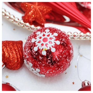 Macro detail of a red Christmas ball with faux snow and silver snowflake pattern