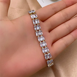 Detail of elegant gold bracelet featuring rectangular cubic zirconia in a prong setting
