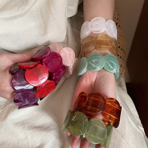 Close-up of chunky resin chain link bracelets in multiple colors on a model's wrist