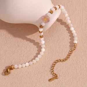 Detail of beaded bracelet with white pearls, pink hexagon bead, and gold lobster clasp
