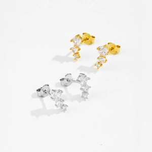 Detailed view of silver and gold geometric stud earrings with three sparkling round stones