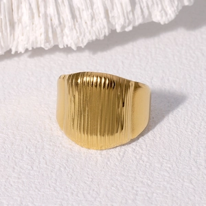 Minimalist gold titanium steel ring with vertical pleated texture on a white background