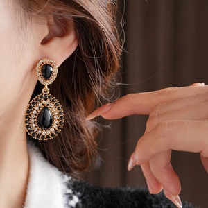 Gros plan de boucles d'oreilles dorées vintage avec pierres noires et diamants