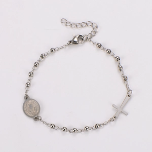 Detailed view of silver bead chain bracelet with religious cross and Saint Benedict medal