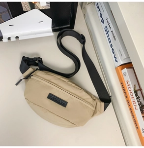 Detail of khaki nylon waist bag with logo patch on a minimalist desk background