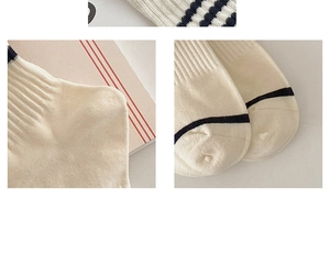 Detailed close-up of ribbed texture and toe seam on cream striped cotton crew socks