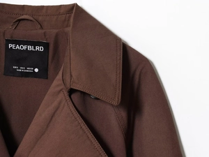 Detailed view of the collar stitching and interior size label on a brown trench coat