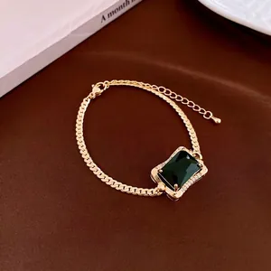 Vintage gold necklace with square green gemstone and zircon accents on brown velvet