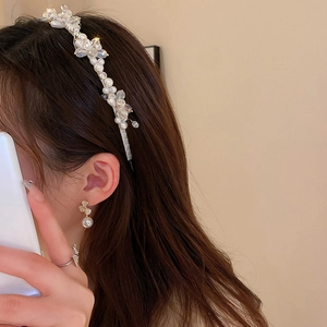 Detail of thin metal headband with pearls and crystals paired with flower pearl earrings