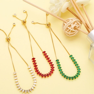 Detail of adjustable gold bracelets with marquise-cut white, red, and green crystals
