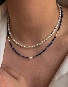Détail d'un collier superposé en perles d'eau douce et pierres bleues sur un chemisier