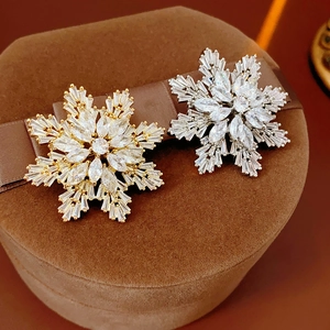 Detailed macro view of gold and silver snowflake brooches with sparkling zircon stones