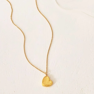 Detailed view of a gold heart pendant featuring a unique honeycomb textured pattern