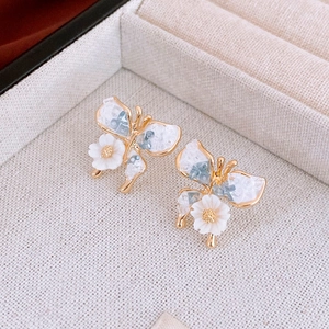 Close-up of golden butterfly flower earrings with blue crystals in a jewelry box