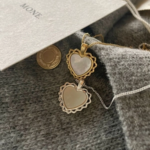 Detailed view of heart pendants with shell inlay and scalloped edges on knit background