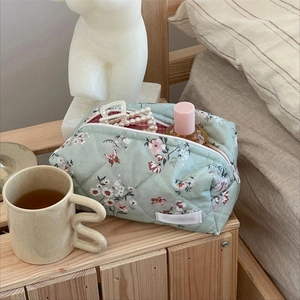 Detail of mint green quilted floral makeup bag with pink flowers and a white zipper