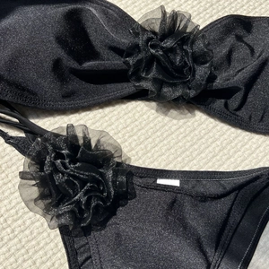 Close-up of black bikini set featuring textured sparkle fabric and mesh 3D flower details