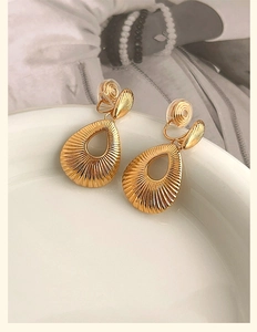 Gros plan détaillé des boucles d'oreilles clips gouttes dorées évidées et texturées