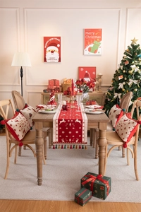 Detail of red and beige knitted table runner with reindeer pattern and fringe accents