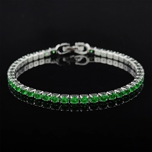 Macro shot of silver tennis bracelet with round cut green emerald zircons and fold-over clasp