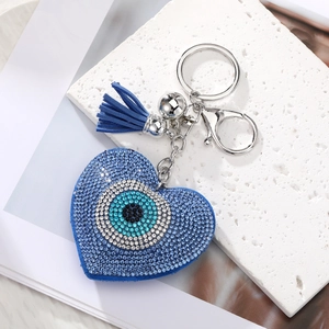 Macro shot of heart-shaped evil eye keychain with blue rhinestones and fringe tassel