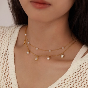 Double-layered gold stainless steel necklace with white flower pendant and pearls on model