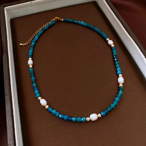 Detail of beaded necklace with blue faceted beads, pearls and gold lobster clasp