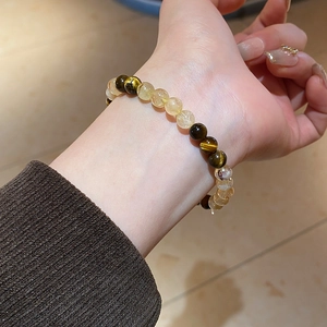 Close-up of a beaded bracelet with tiger eye stones and citrine crystals on a wrist