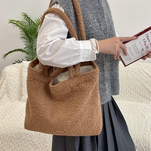 Dettaglio della borsa tote marrone in pile bouclé con texture e etichetta logo
