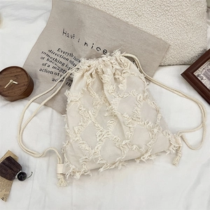 Detail of cream tassel drawstring backpack with textured diamond quilted fabric design