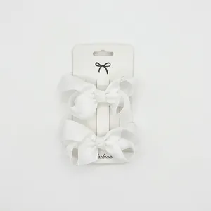 Detail view of two white grosgrain ribbon bows on a fashion display card