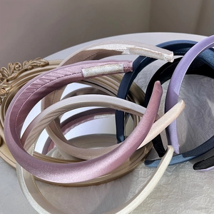 Stack of multi-colored satin padded headbands in pink and blue on a mirror surface