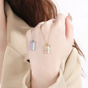 Detailed shot of two bear pendant necklaces in gold and silver with pink and white enamel