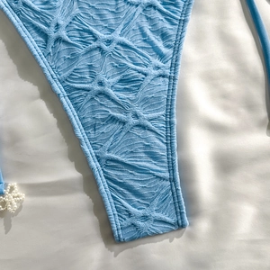 Close-up of blue textured bikini fabric with 3D honeycomb pattern and pearl flower detail