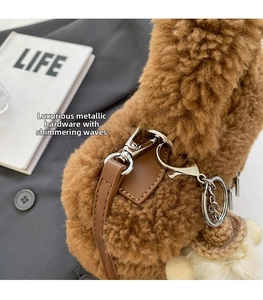 Detail view of brown plush bucket bag with leather strap and white woven ball charm