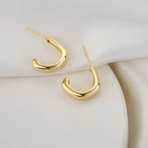 Minimalist 14K gold plated C-shaped earrings displayed on white silk fabric